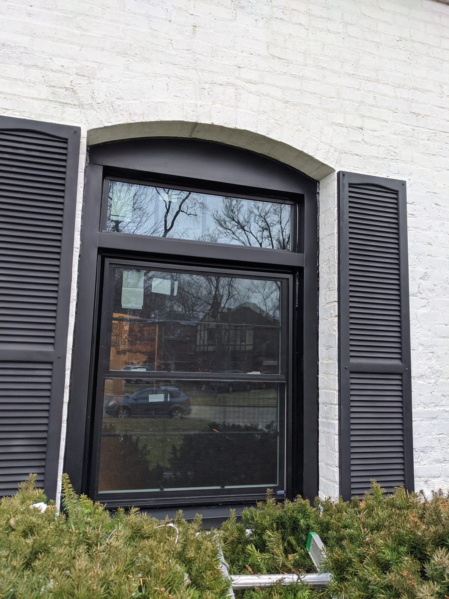 Black arched replacement window installed in brick exterior
