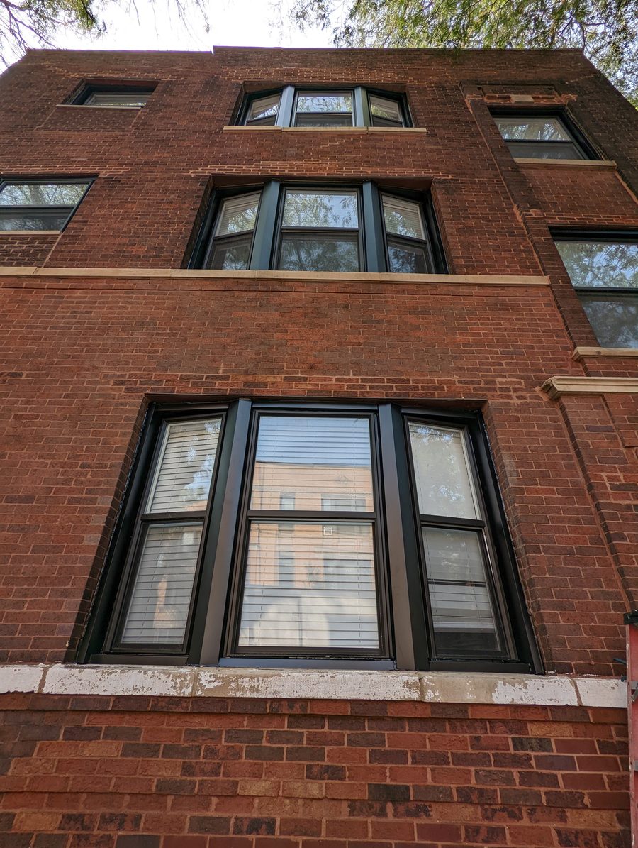 Black bay and double-hung replacement windows installed in a brick building