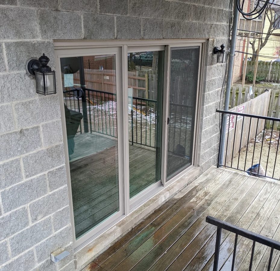 Gray sliding patio door replacement opening onto a deck