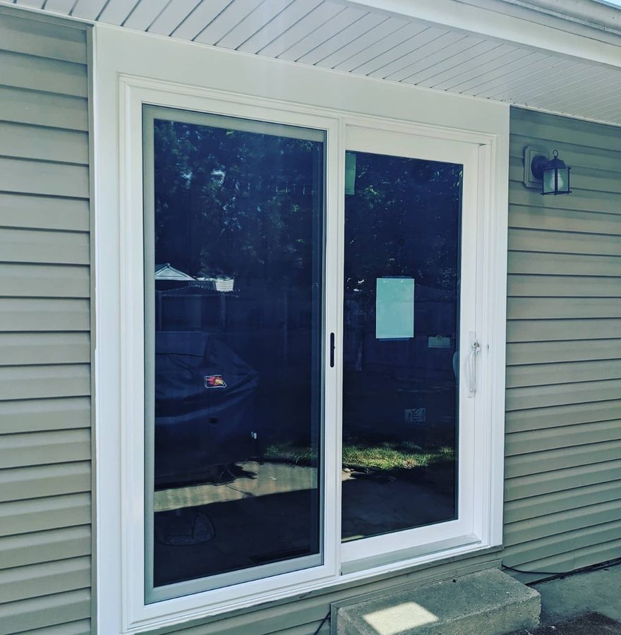 White sliding patio door replacement on siding exterior